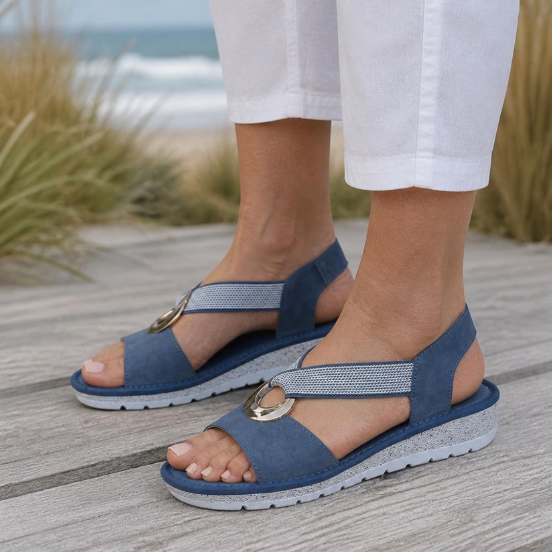 Tilda wedge sandals in Blue worn with white cropped pants on a coastal boardwalk