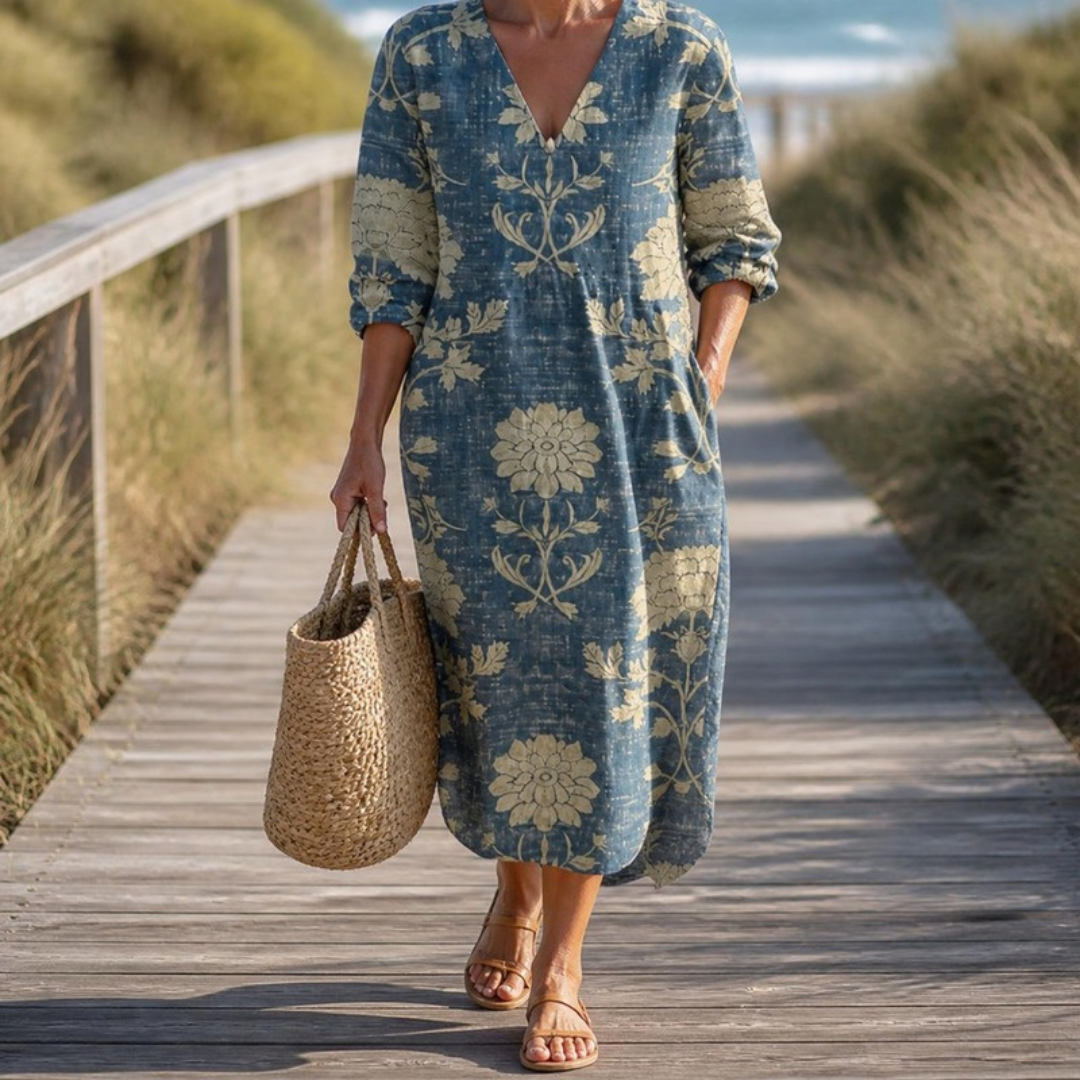 Winifred midi dress in Blue worn on a coastal boardwalk with a woven bag